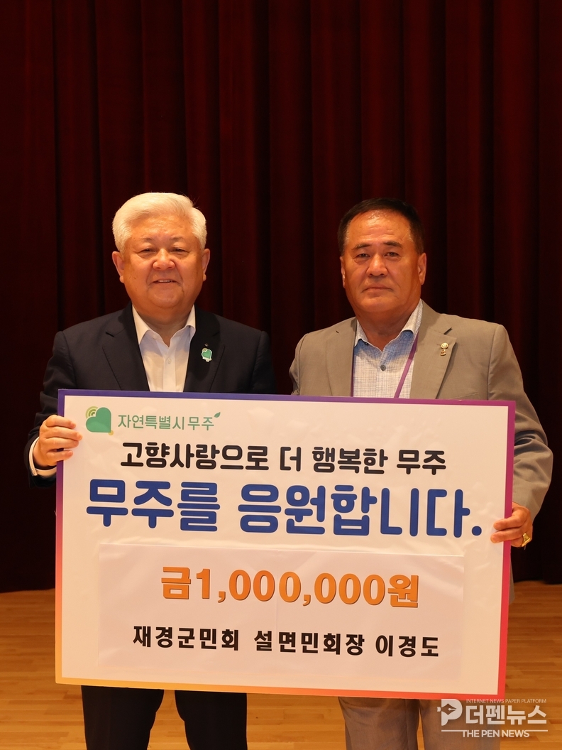“이경도 재경무주군민회 설천면민회장이 제29회 무주반딧불축제 현장에서 사랑기부금 100만 원을 전달하고 있습니다.(무주군 제공)”
