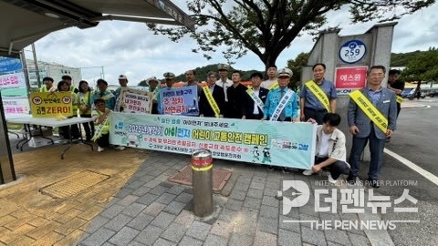 어린이 보호구역에서 캠페인 참여자들이 횡단보도 일단멈춤과 과속금지 등 교통안전 메시지를 홍보하고 있다.