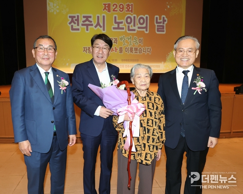 우범기 전주시장이 제29회 전주시 노인의날 기념식에서 100세 어르신 김옥순 씨에게 청려장을 전달하며 축하의 꽃다발을 증정하고 있다.