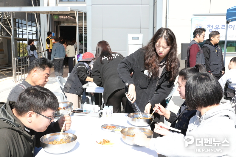 한사발(한마음을 사랑하는 발전 위원회) 회원이 자장면을 먹기 편하도록 가위로 잘라주며 따뜻한 손길을 전하고 있다.